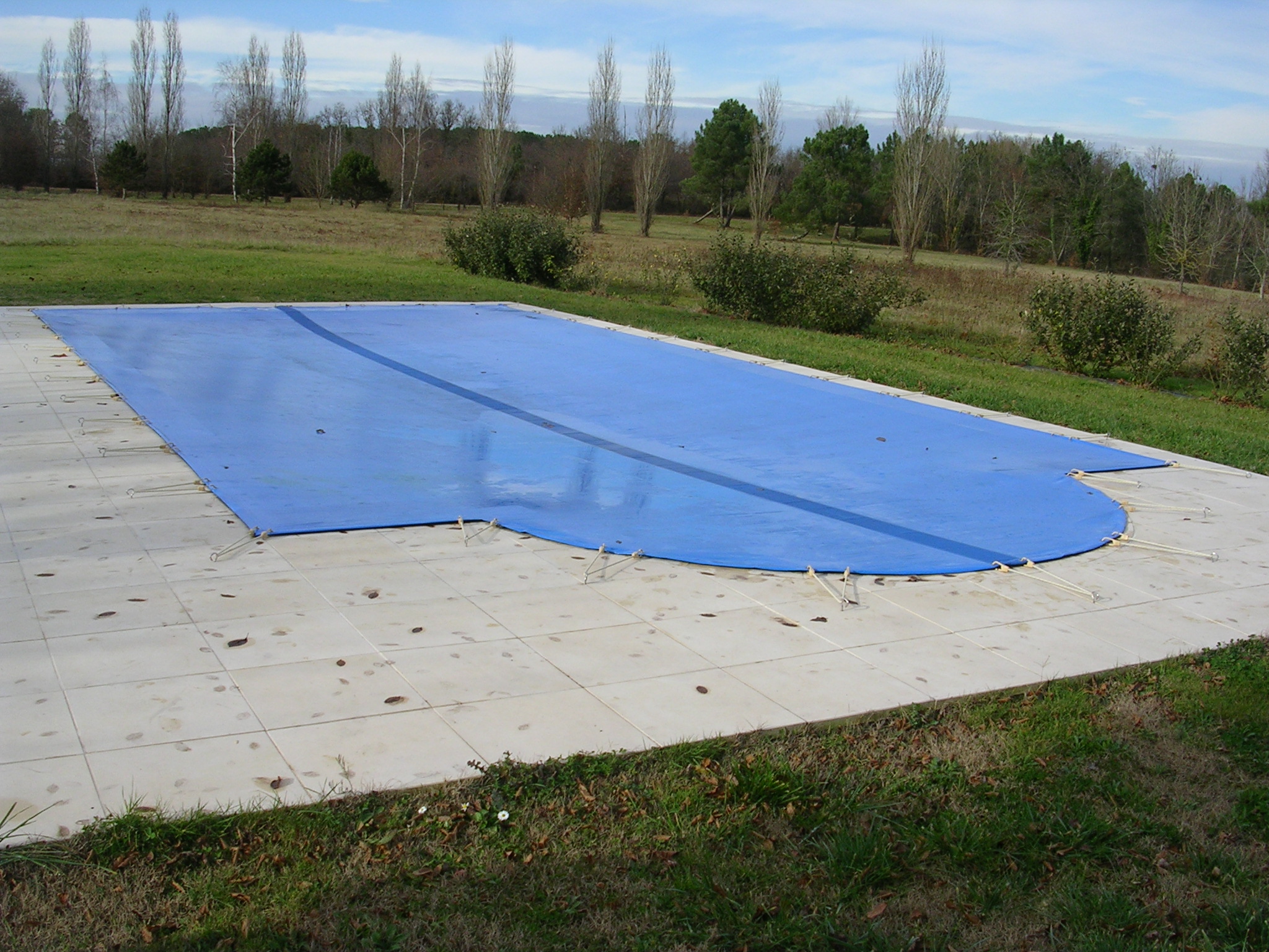 Bâche d'hivernage opaque bleue tendue et fixée sur une piscine pour l'hivernage passif